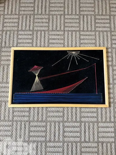 Vintage handmade string art wall decor on black velvet background