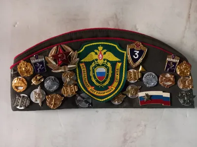 Russian garrison cap decorated with various military pins and patches