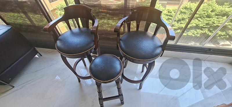 "Traditional wooden bar stools with armrests and a matching stool."