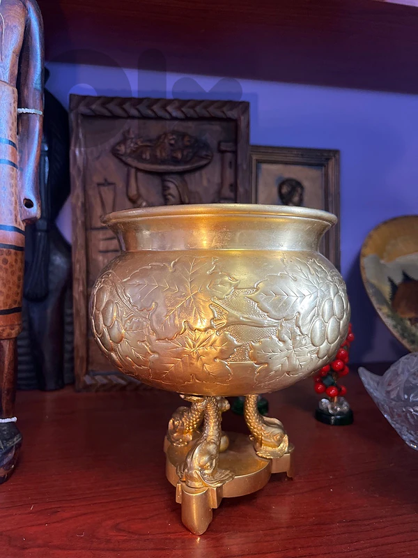 Brass jardinière features embossed grape and leaf motifs.